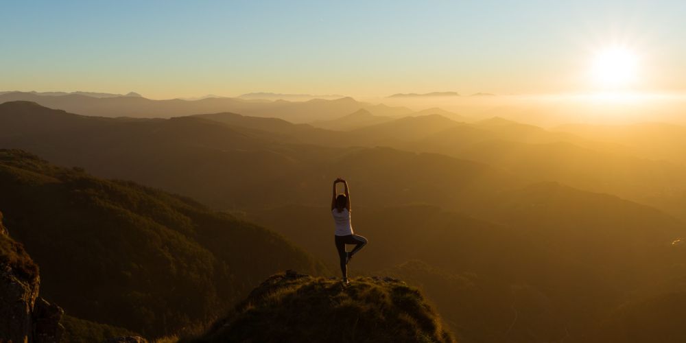Yogi en haut d'une montagne pour illustrer un article sur comment trouver l'équilibre vie pro / vie perso en tant que digital nomad.